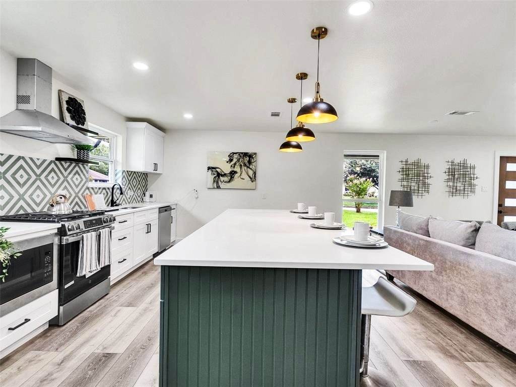 Braeswood Renovation — Kitchen opening to the living room, anchored by the green island.