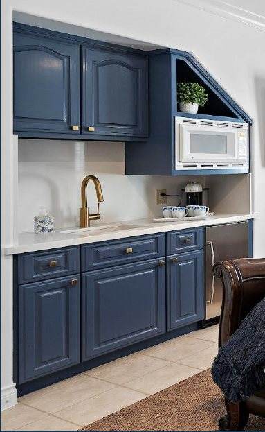 Lakes of Parkway Residence — Detail of the navy kitchenette — raised-panel cabinetry, gold gooseneck faucet, and quartz counters.