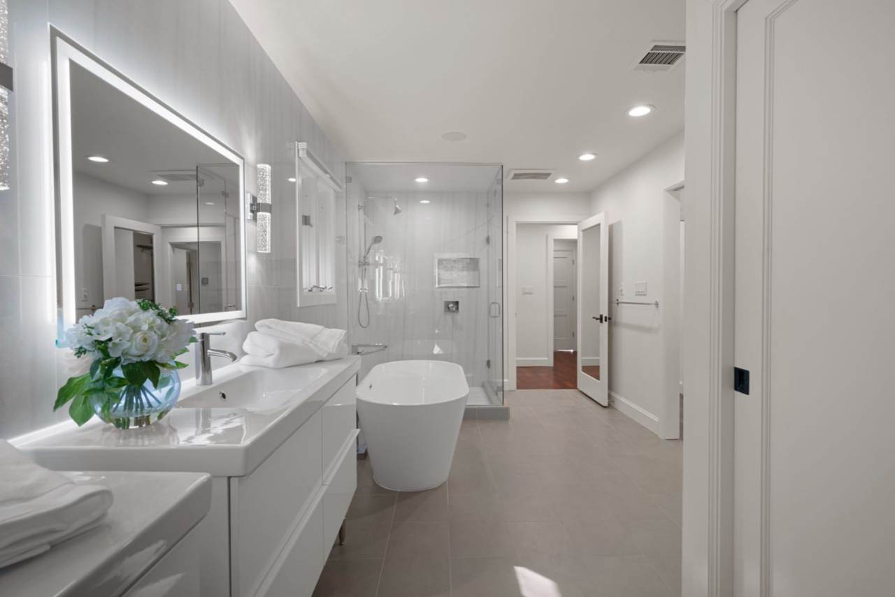 Memorial Residence — A spa-like primary bath with a freestanding soaking tub, frameless glass shower, and large-format marble tile.