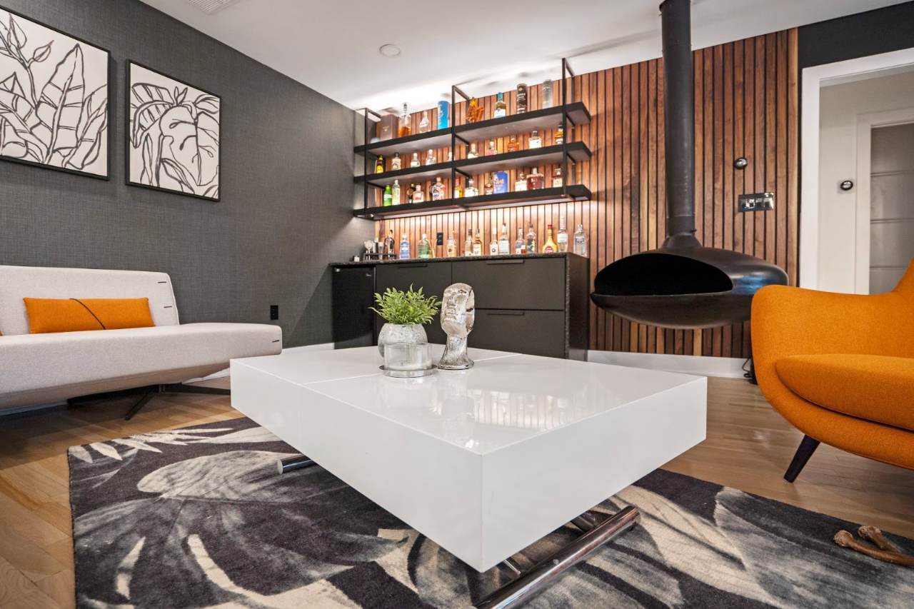 River Oaks Transformation — Warm contemporary living room with charcoal sofa and saffron accents