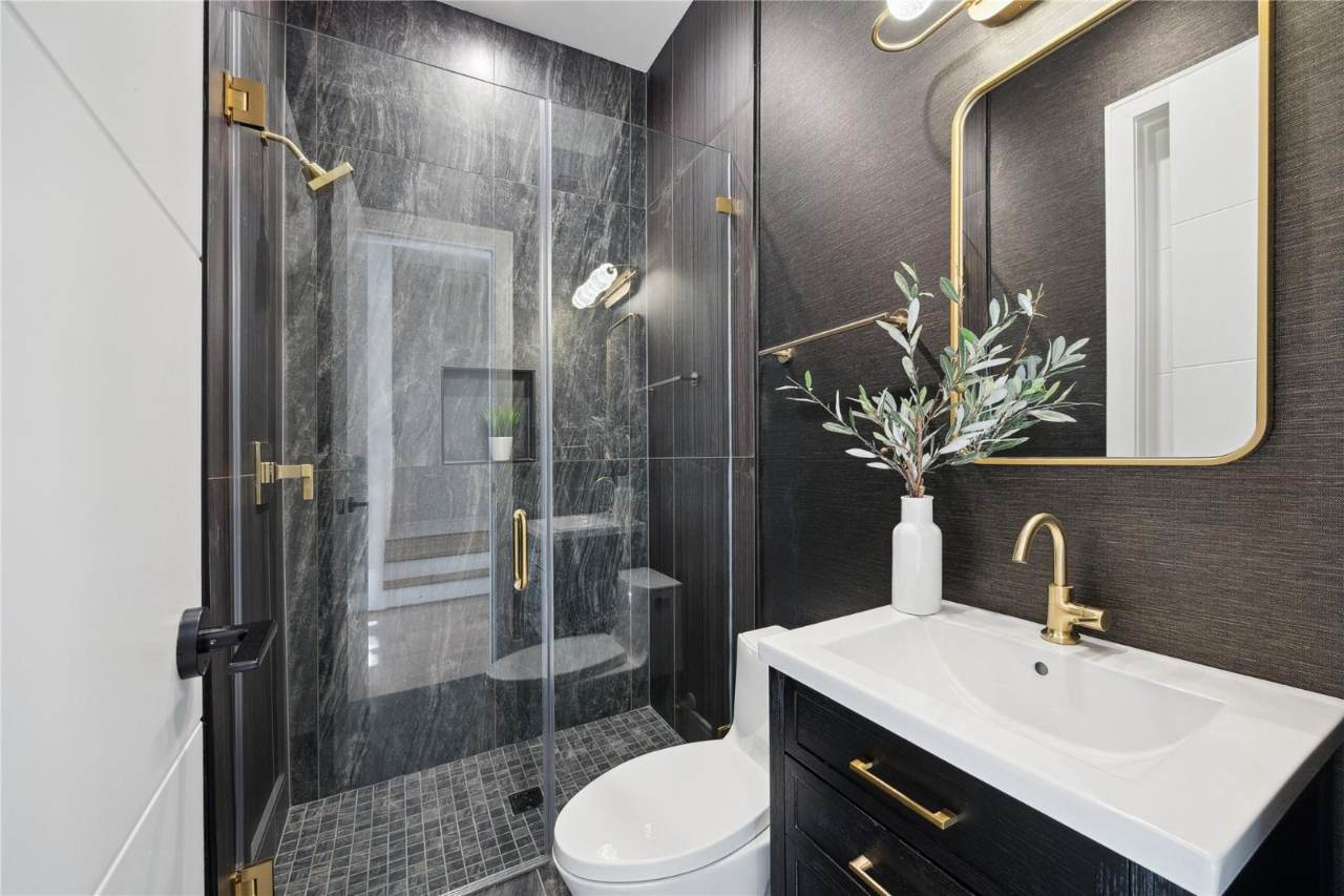 West University Custom Home — Moody black-tiled powder bath with marble and brass accents